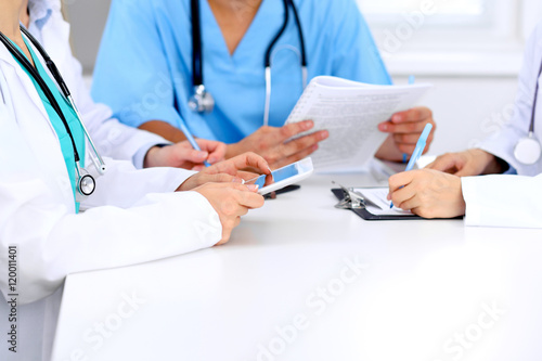 Group of doctors at medical meeting. Close up of physician using tablet computer.