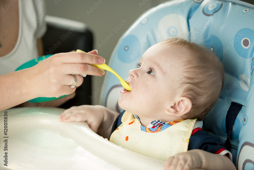 Cute baby sitting in highchair and opening mouth for spoon with Cute baby sitting in highchair and opening mouth for spoon with