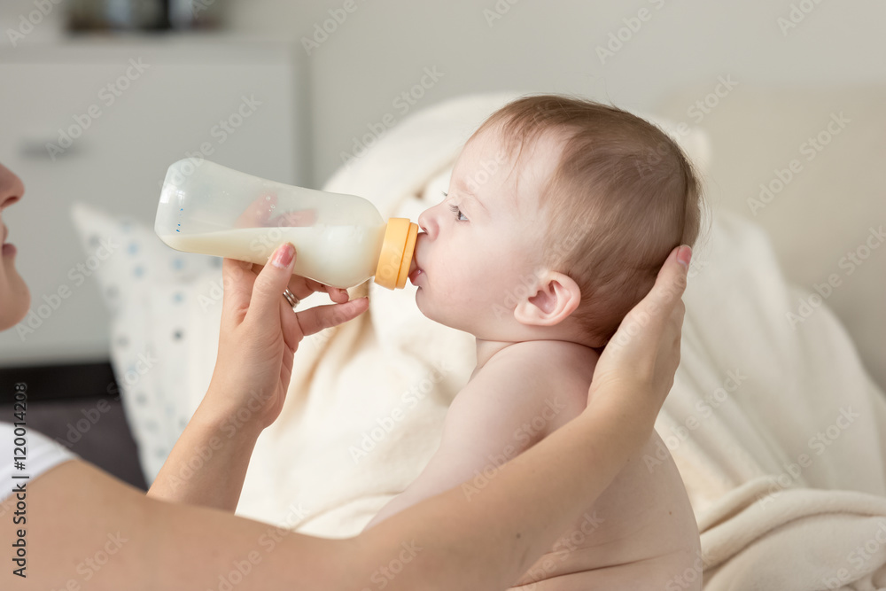 Φωτογραφία Closeup of mother giving milk from bottle to her baby son sittin