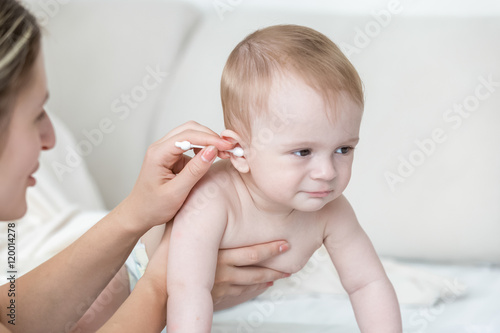 Young mother cleaning baby's ear with cotton swab after bathing
