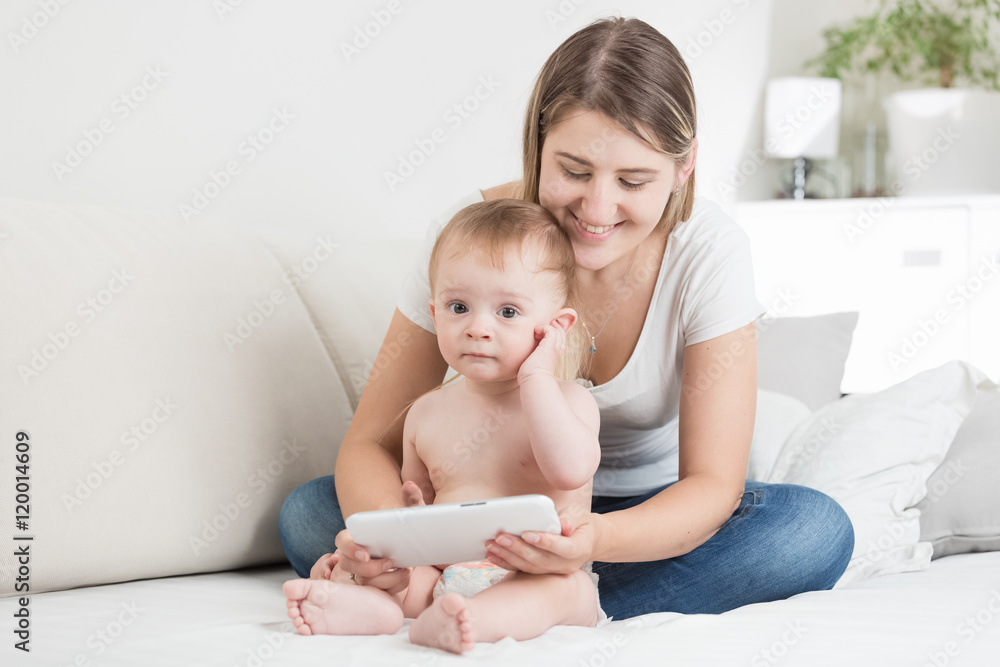 Young mother and baby boy in diapers using tablet pc Young mother and baby boy in diapers using tablet pc