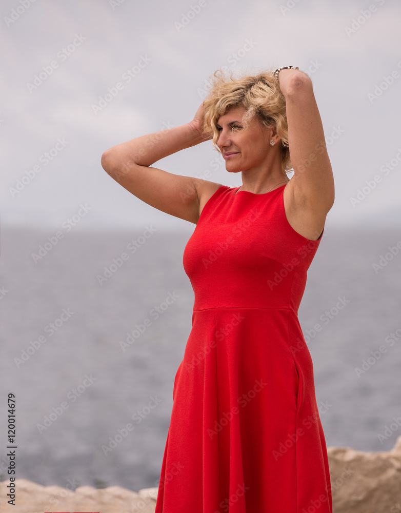 Beautiful woman in red dress near of the sea Beautiful woman in red dress near of the sea