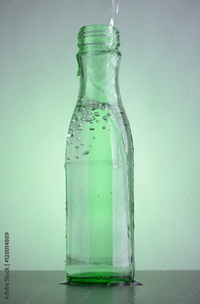 Green bottle with clean drinking water on the table. Bubbles in the glass transparent bottle. Green bottle with clean drinking water on the table. Bubbles in the glass transparent bottle.