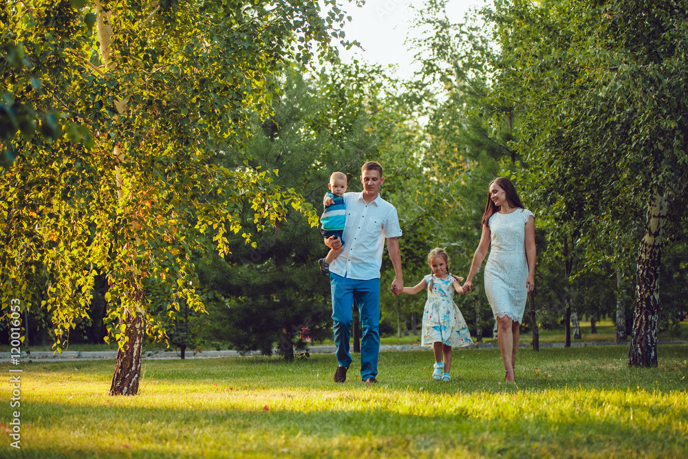 Fototapeta premium Happy young family of four people walking and having fun in the park