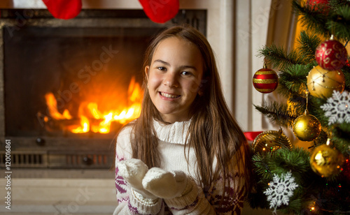 Obraz na plátně Portrait of smiling girl in sweater and gloves posing at burning