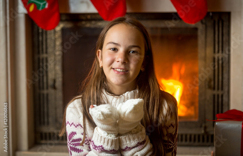 Fotografie Beautiful girl in woolen sweater and gloves sitting at burning f