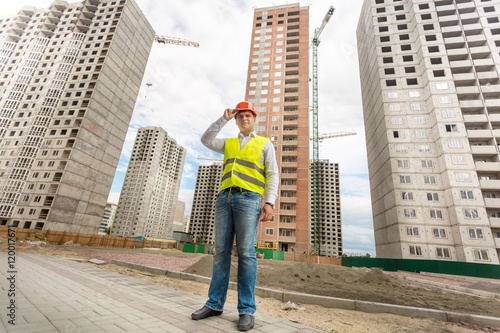 Businessman in hardhat and safety vest standing on building site