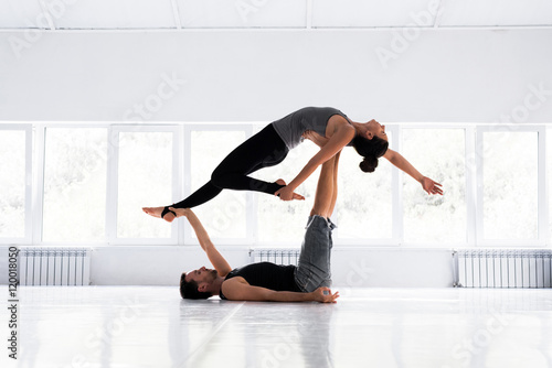 Couple practicing acro yoga in white studio. Acro yoga concept. photo