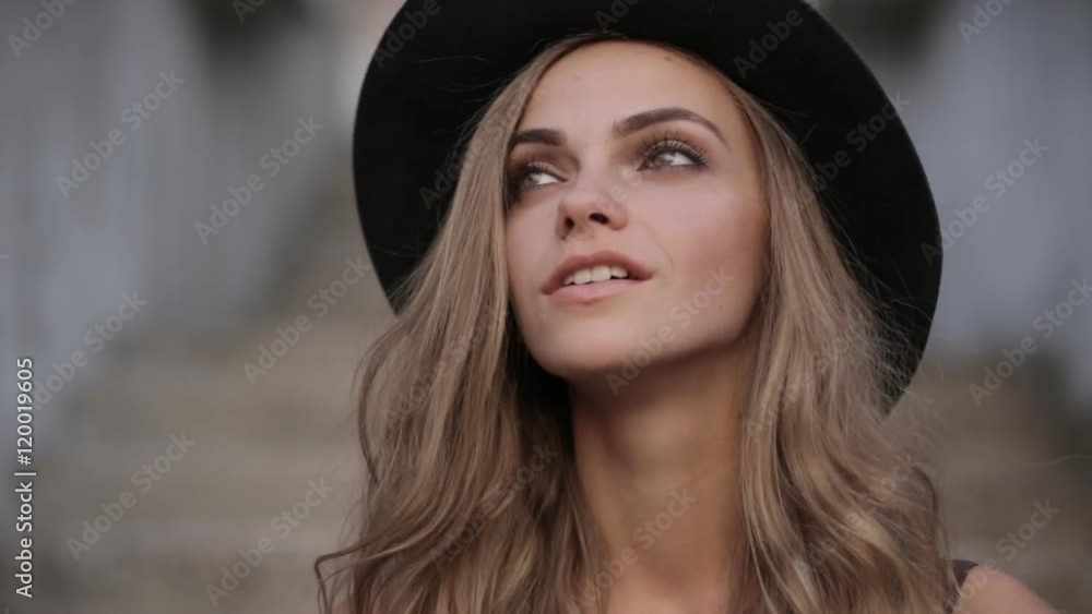 pretty young girl in a black hat looking up on a gray background pretty young girl in a black hat looking up on a gray background