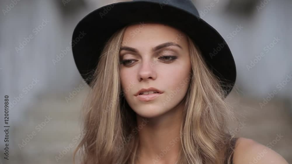pretty young girl in a black hat looking up on a gray background pretty young girl in a black hat looking up on a gray background