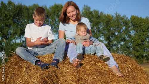 mother with children playing on a haystack