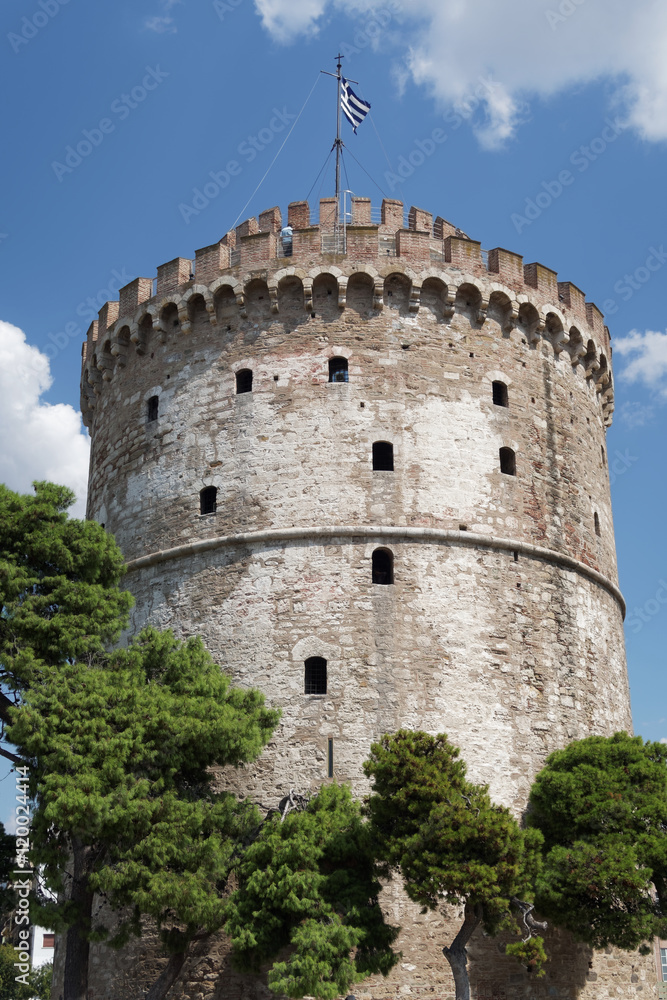 Thessaloniki, Greece. The White Tower with Greek flag waving on top. The White Tower is the landmark of Thessaloniki.