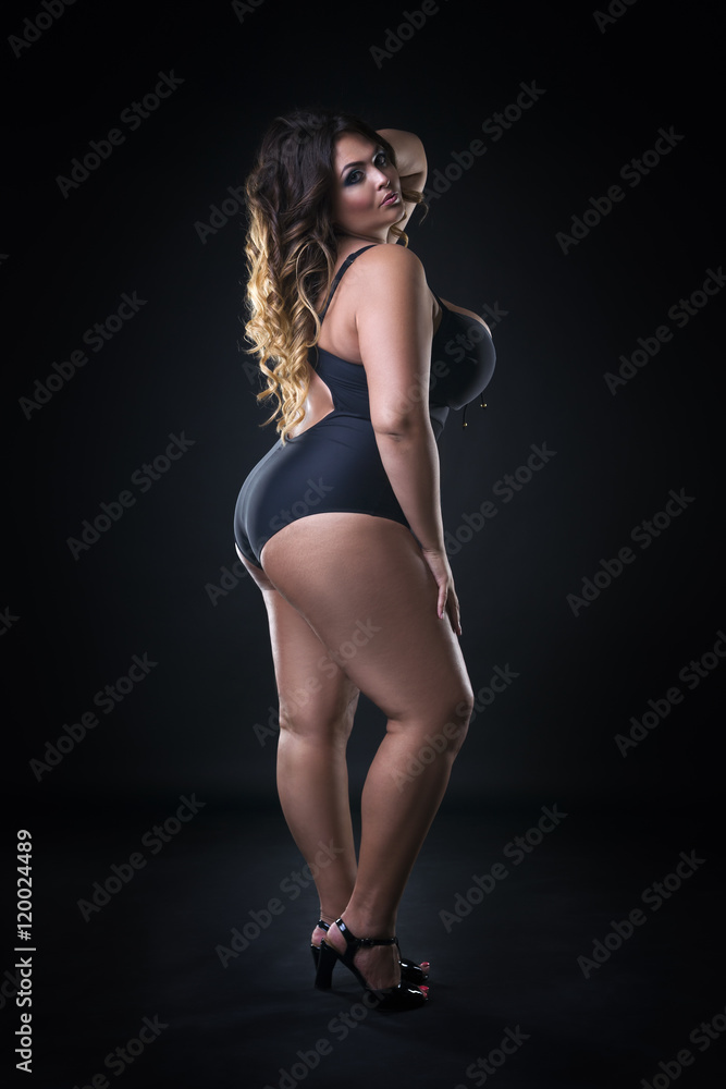 Obraz premium Young beautiful caucasian plus size model in swimsuit, xxl woman on black background