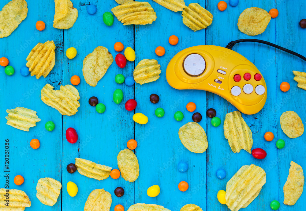 Game controller, chips and candy on a blue wooden background. fast food,  snacks, not unhealthy food. Colored candy. Snack between games. Colored  pills. Video game console GamePad. Stock Photo | Adobe Stock