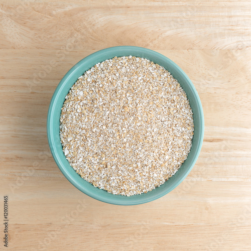 Dry oat bran hot cereal in a bowl atop a wood table.