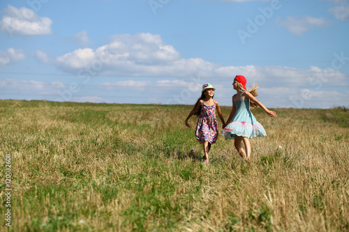 Two little girls running in summer field