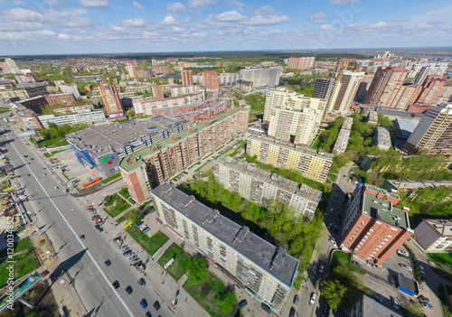 Aerial city view with crossroads and roads, houses, buildings, parks and parking lots, bridges. Copter shot. Panoramic image.