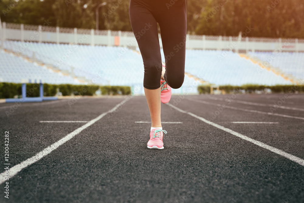 Fototapeta premium Woman running in pink sneakers on a stadium