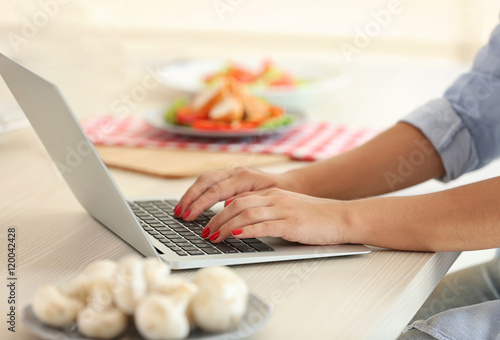 Girl with laptop on kitchen. Food blogger concept photo