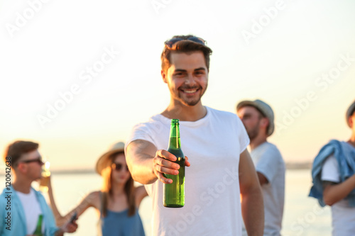 Handsome young man with friends hanging out at beach