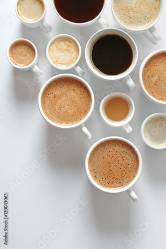 Cups of coffee on white background, top view