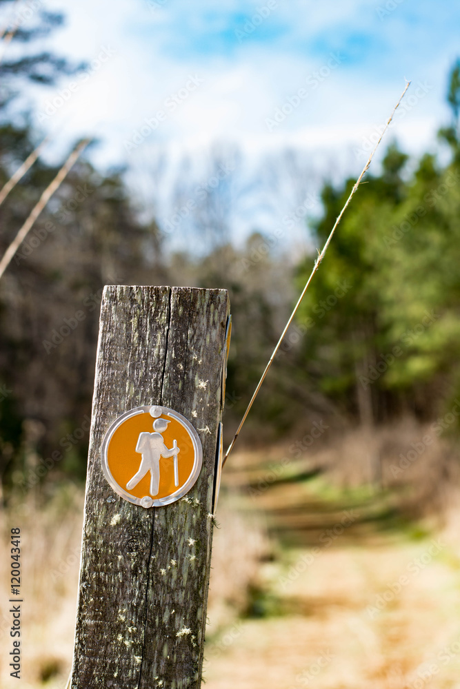 Trail marker with the hiking trail in the background. This photo was taken in North Carolina.