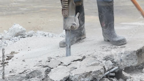 Construction worker removes excess concrete with drilling machine