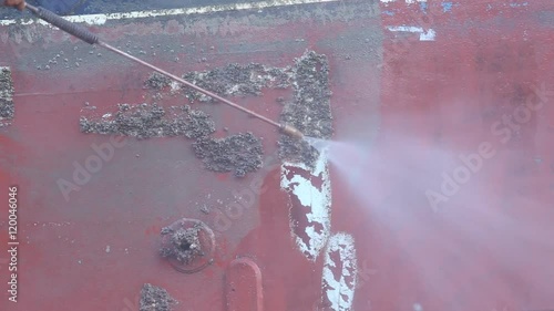 A man working on pressure washer to cleaning boat hull barnacles antifouling and seaweed at the harbor