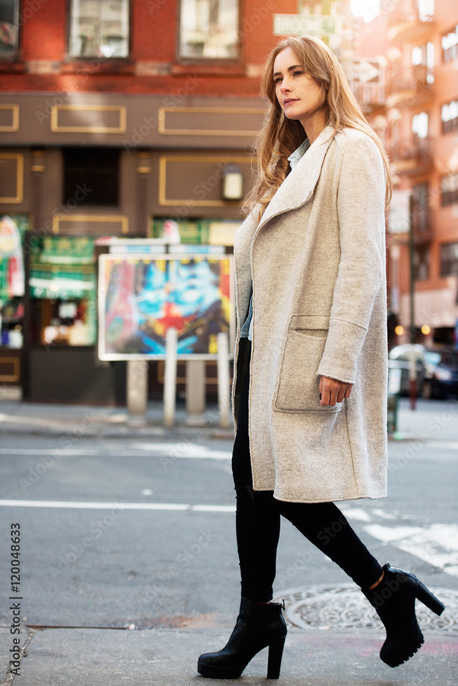 Fototapeta premium Young adul beautiful woman walking on city street wearing casual street style autumn outfit with grey jacket and black jeans