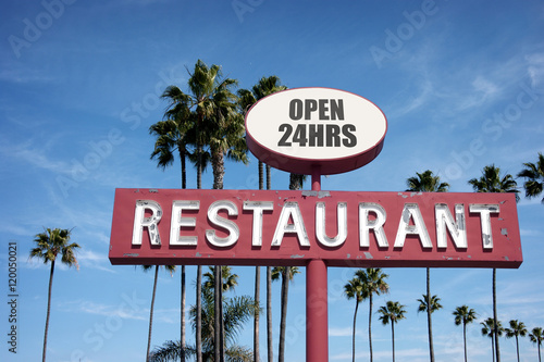 aged and worn vintage photo of old neon restaurant sign with palm trees