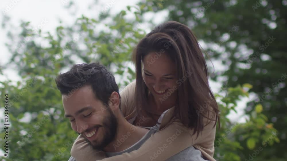 Laughing and Smiling Couple Having Fun Outdoors. Man Giving Girl Piggyback Ride. Shot on RED Cinema Camera in 4K (UHD). Laughing and Smiling Couple Having Fun Outdoors. Man Giving Girl Piggyback Ride. Shot on RED Cinema Camera in 4K (UHD).