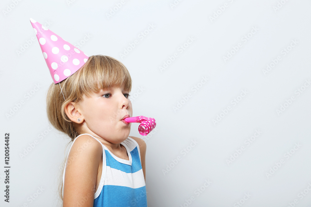 Portrait of little girl in birthday cap on grey background Portrait of little girl in birthday cap on grey background