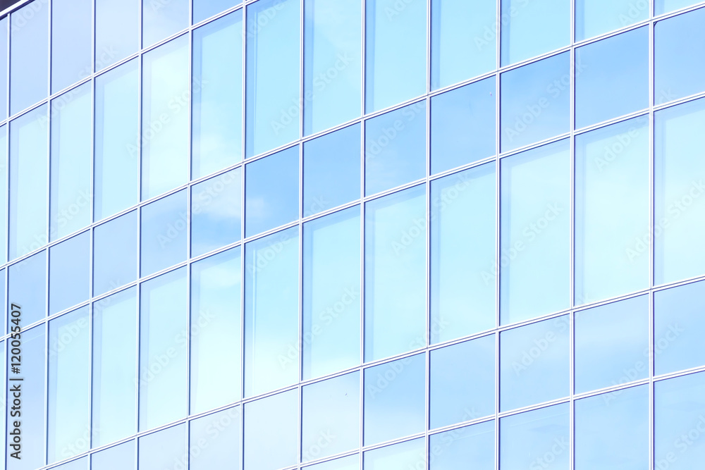 The glass facade of a skyscraper with a mirror reflection of sky windows The glass facade of a skyscraper with a mirror reflection of sky windows