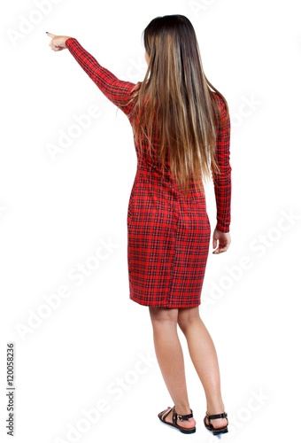 Back view of pointing woman. girl in red plaid dress shows an index finger upwards.