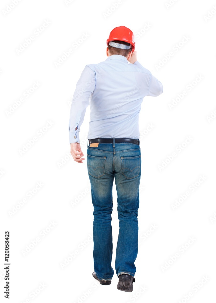 Back view of running engineer in helmet. Walking guy in motion. Bearded businessman in a white shirt and a helmet runs away from the frame. Back view of running engineer in helmet. Walking guy in motion. Bearded businessman in a white shirt and a helmet runs away from the frame.