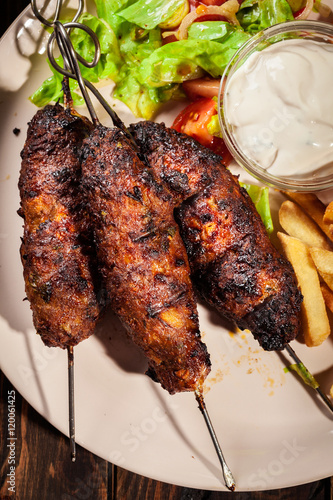 Grilled shish kebab served with fried chips and salad photo