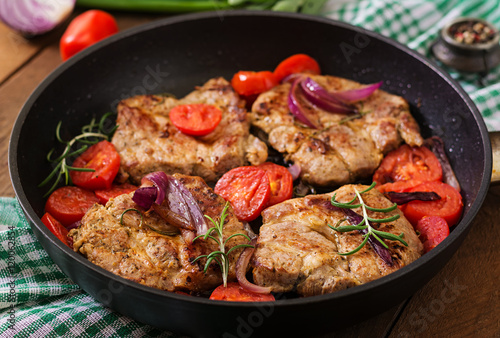 Juicy pork steak with rosemary and tomatoes on pan