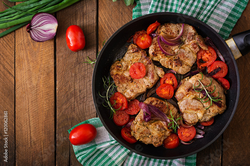 Juicy pork steak with rosemary and tomatoes on pan. Top view