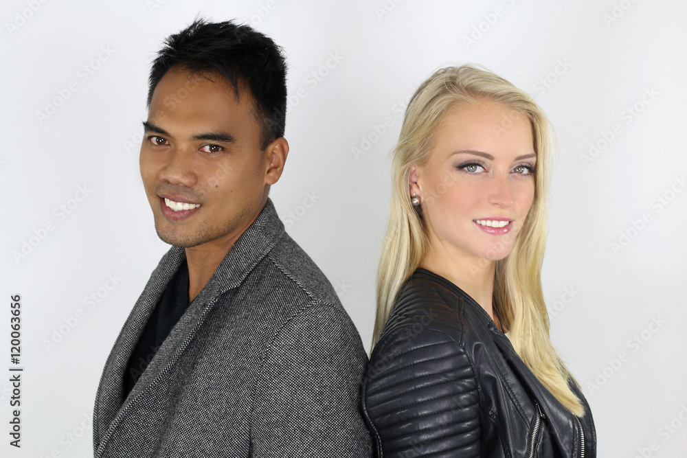 Jeune couple mixte posant devant un fond blanc Jeune couple mixte posant devant un fond blanc