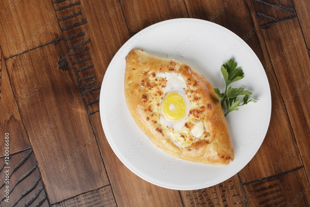 Khachapuri - traditional georgian pie with potatoes and cheese. Cake on a white plate. Wooden background