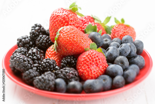 red plate full of ripe berries selective focus