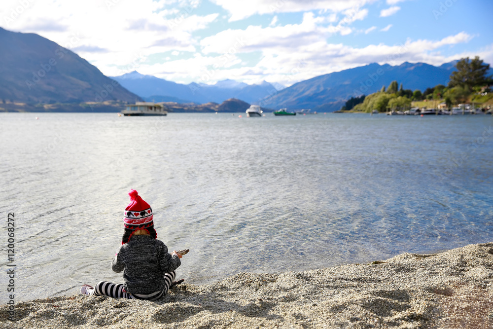 Fototapeta premium Little girl is playing by the water of Lake Wanaka, New Zealand