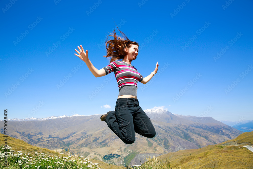 Happy Young woman jumping with Mt Aspiring landscape view in Wanaka, New Zealand Happy Young woman jumping with Mt Aspiring landscape view in Wanaka, New Zealand