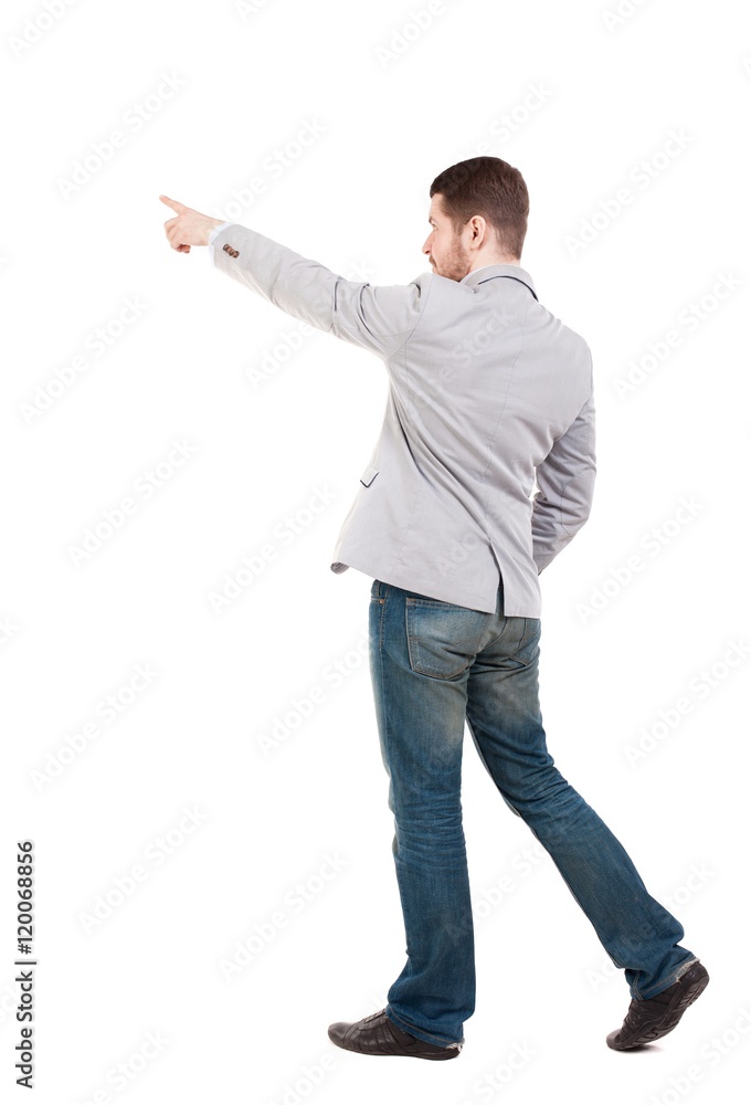 Back view of going man in a gray jacket is pointing in front of him. Back view of going man in a gray jacket is pointing in front of him.
