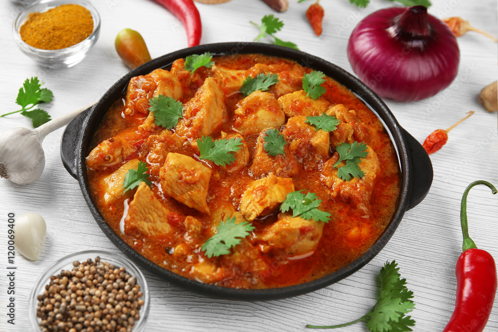Chicken curry with vegetables on wooden background
