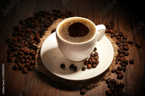 Cup of coffee with beans on wooden background