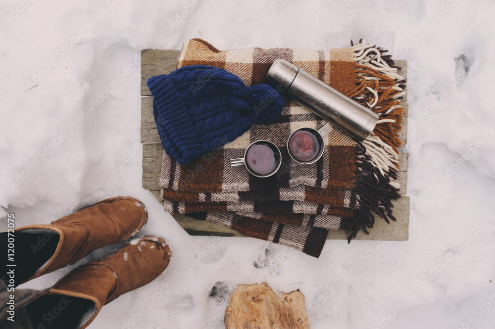 winter picnic on the snow. Hot tea, thermos and snowball heart on cozy warm blanket. Outdoor seasonal activities.