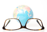 eyeglasses and blurred globe at the back on white