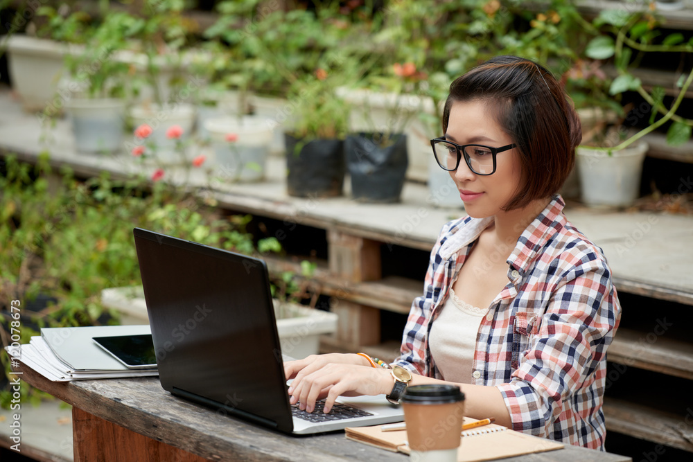 Asian young copywriter working on computer outdoors Asian young copywriter working on computer outdoors