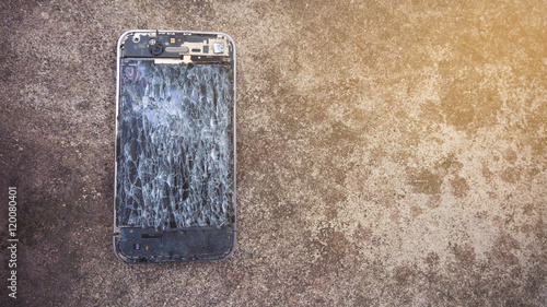 Broken smartphone on the cement floor with broken display.